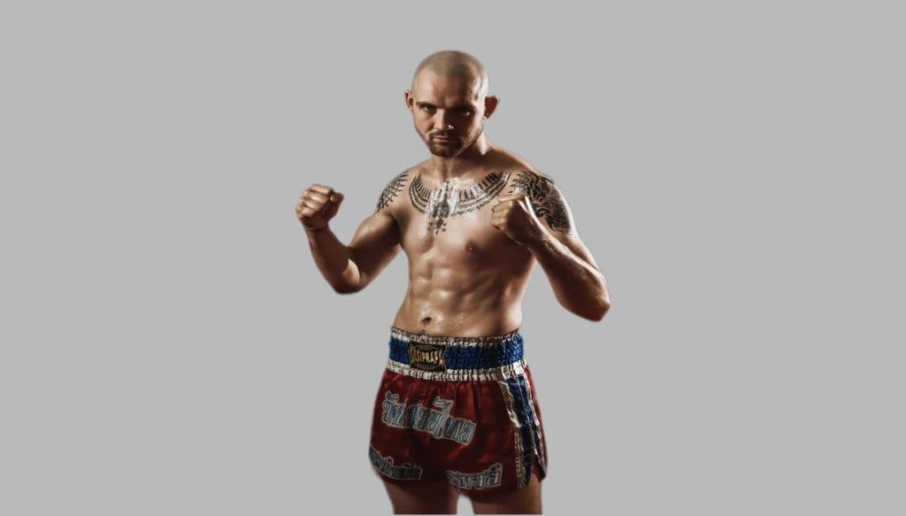 A man in boxing shorts gearing up for a strong return to Muay Thai training in Cornwall and beyond after Christmas, posing for a photo.